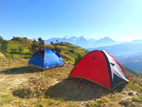 two tents on a hill with mountains in the background at mountain view willcacocha lodge in Huaraz