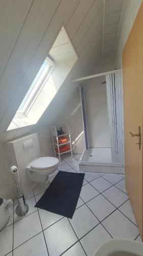 a attic bathroom with a toilet and a skylight at Ferienwohnung Hahnentange in Rhauderfehn