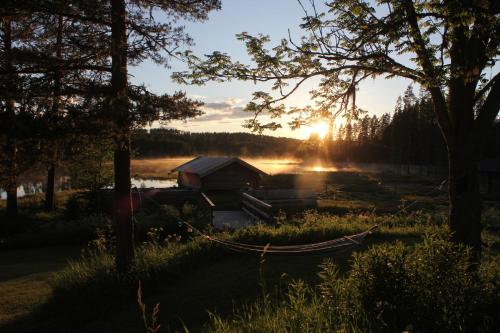 a hammock in front of a cabin on a lake at Rustika strandstugor utanför Rättvik in Rättvik