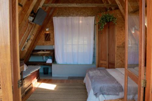 um pequeno quarto com uma cama e uma janela em Sítio CRIA - Hospedagem Sustentável & Experiências Rurais em Três Coroas