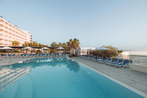a large swimming pool with chairs and a hotel at Romana Beach Resort in Makarska