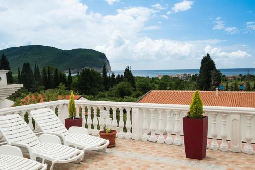 Un balcón con sillas blancas y vistas al océano. en Hotel Wellness & Spa Angelo Gabriel, en Petrovac na Moru