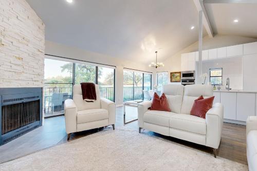 a living room with two white chairs and a fireplace at Way to the Bay in Horseshoe Bay