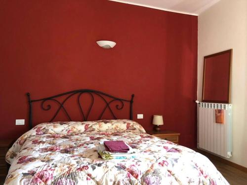 een slaapkamer met een bed met een rode muur bij Ca' Cuore in Monferrato in Serralunga di Crea