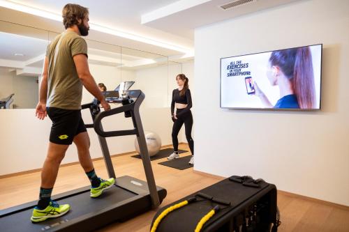 a man walking on a treadmill in front of a screen at Wellness Smart Suites in Bolzano