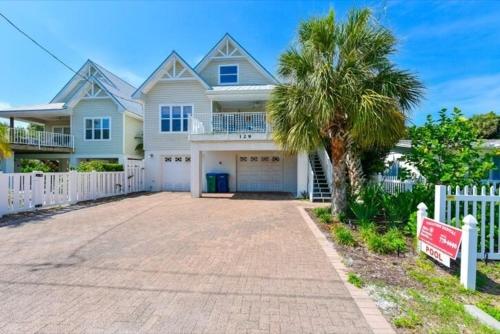uma casa branca com uma palmeira e uma entrada em Two For Sea House #54538 Home em Holmes Beach