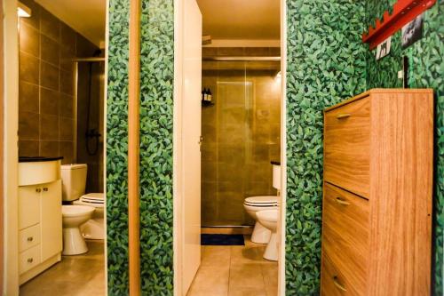 a bathroom with two toilets and a green wall at Luminoso con Cochera, Balcón, Hamaca y Parilla in Paraná