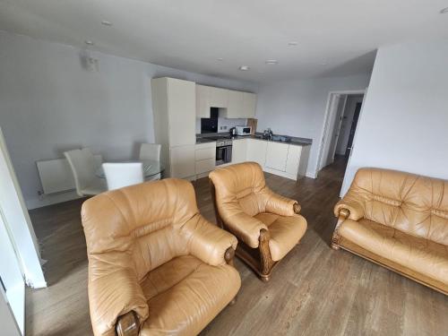 a living room with two chairs and a kitchen at Hippersley Point, Tilston Bright Square, Abbey Wood, London SE2 9DR, UK in London