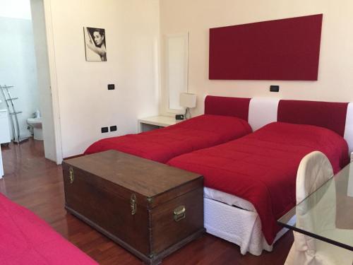 a bedroom with two beds with red sheets at Il Giardino Nascosto in Busto Arsizio