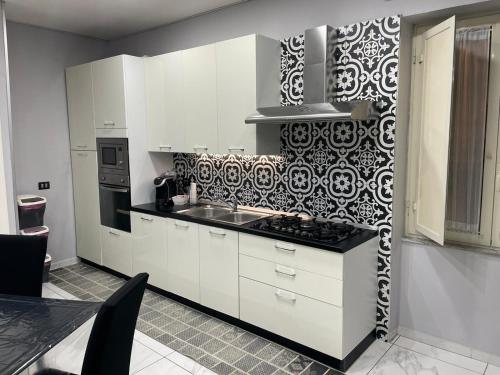 una cocina con armarios blancos y una pared estampada en blanco y negro. en La Magica, en Nápoles