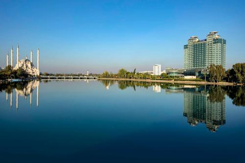 ein großer Wasserkörper mit Gebäuden im Hintergrund in der Unterkunft Adana HiltonSA Hotel in Adana