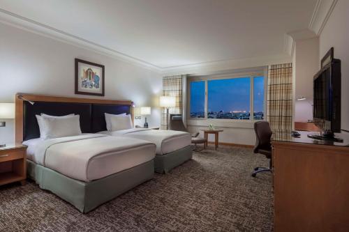a hotel room with a bed and a large window at Adana HiltonSA Hotel in Adana