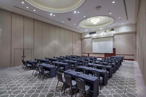 a conference room with tables and chairs and a screen at Adana HiltonSA Hotel in Adana