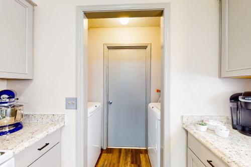 a kitchen with white cabinets and a hallway with a door at Casa de Cowboy in Stillwater