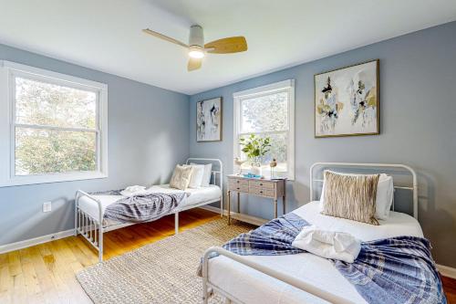 2 łóżka w pokoju z niebieskimi ścianami i oknami w obiekcie Serene Cottage w mieście Charleston