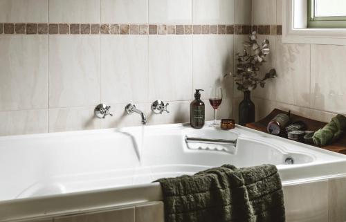 a bath tub with a towel and a glass of wine at Hey Little Joe - Cosy Retreat with Mountain Views in Warburton