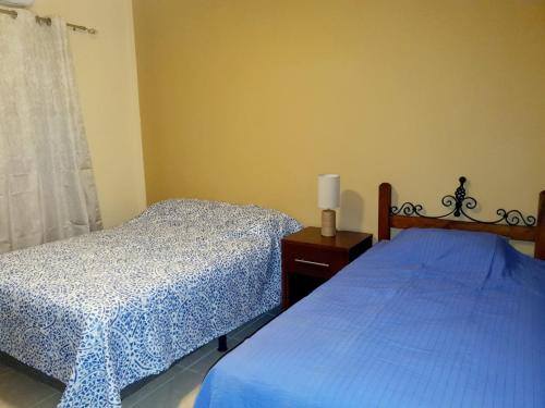 a bedroom with two beds with blue sheets and a window at Como el Calor de tu hogar in San Pedro Sula