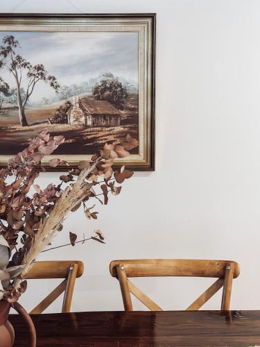 a painting hanging on a wall next to two chairs at Hey Little Joe - Cosy Retreat with Mountain Views in Warburton
