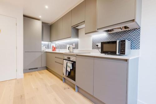 a kitchen with white cabinets and a microwave at 4-Level Luxury 2 Bedroom House Sleeps 6, Rooftop, Harry P & Free Parking in Watford