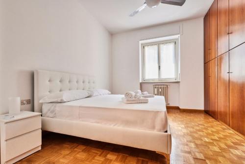 una camera bianca con un grande letto e una finestra di L'Antico Casolare - Vicino M3 e Fondazione Prada a Milano
