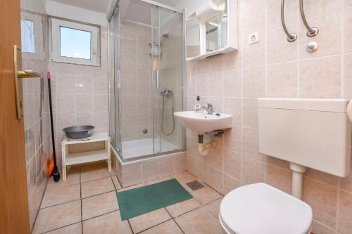 a bathroom with a toilet and a sink and a shower at Apartments Karleusa in Rogoznica