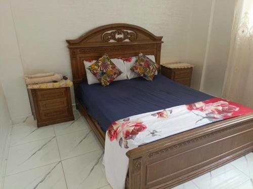 a bedroom with a wooden bed with flowers on it at Sweet Room Airport 5 in Deroua