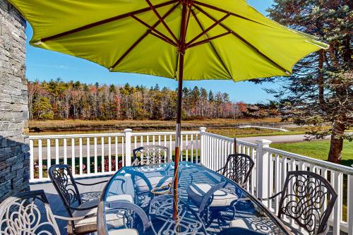 a table with a yellow umbrella on a balcony at Barefoot Bliss in Kennebunk
