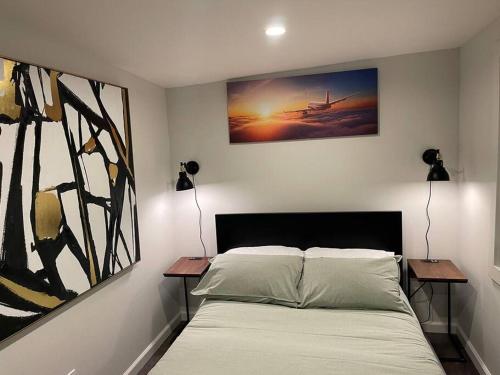 een slaapkamer met een bed met 2 tafels en een schilderij bij Cozy 1BR ADU Nestled in Foothill in Oakland