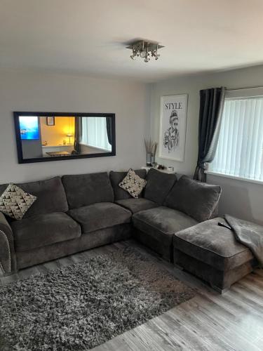 a living room with a brown couch and a television at Fantastic full 3 bedroom modern apartment in Belfast
