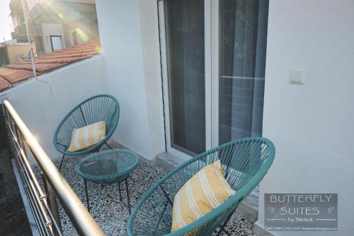 two green chairs sitting on a balcony with a window at BUTTERFLY SUITES by STELIOS in Keramotí