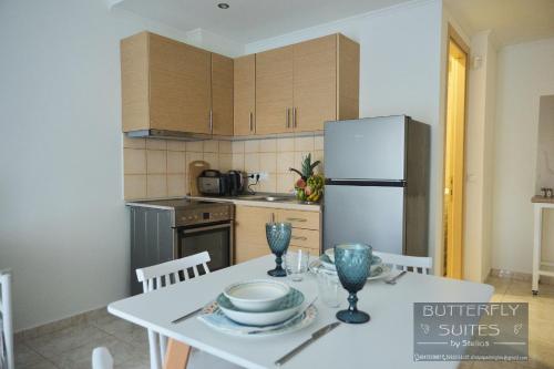 a kitchen with a white table and a refrigerator at BUTTERFLY SUITES by STELIOS in Keramotí