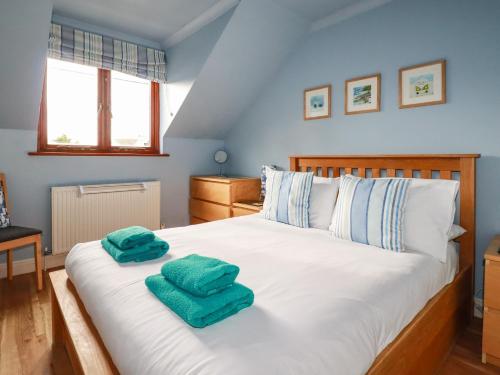 a bedroom with a bed with two green towels on it at Sunflower Cottage in Wadebridge