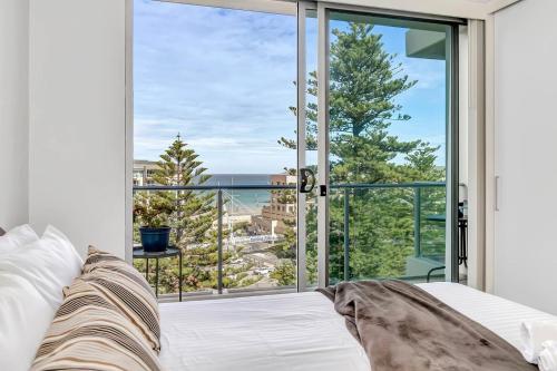 um quarto com uma cama e uma grande janela em Waterfront Resort-Style Living at Glenelg Beach em Glenelg
