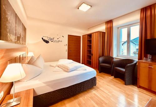 Habitación de hotel con 1 cama y 2 sillas en TirolerHof Dölsach, en Lienz