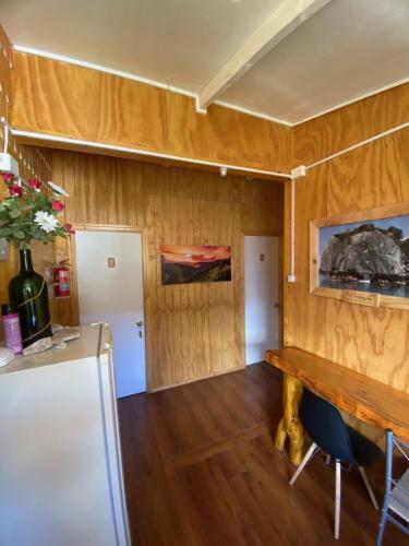 Zimmer mit Holzwänden, einem Tisch und einem Kühlschrank in der Unterkunft Los alamos in Puerto Tranquilo