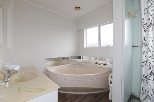 a white bathroom with a tub and a sink at Woodward House Taupo in Taupo