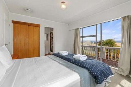 a bedroom with a large bed and a balcony at Woodward House Taupo in Taupo