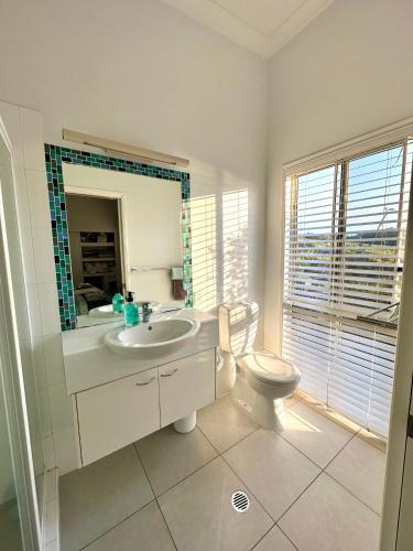 a bathroom with a toilet and a sink and a mirror at Blue Ocean View Beach House, Tangalooma Resort in Tangalooma