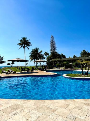 a large swimming pool with palm trees and a beach at Blue Ocean View Beach House, Tangalooma Resort in Tangalooma