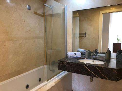 La salle de bains est pourvue d'un lavabo et d'une douche en verre. dans l'établissement Forum Ocean View Apartment, à Funchal