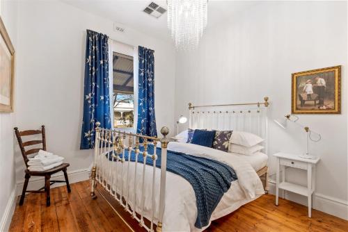 a bedroom with a bed with blue curtains and a chair at KING44 - King Charming in Fremantle