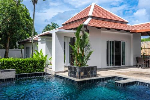 a villa with a swimming pool in front of a house at Luxurious Residence Rawai in Phuket Town