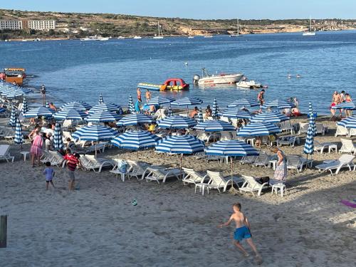 a group of people on a beach with umbrellas at Seaview Family Apartment, Pool, Easy Access to the Sea, Near Mellieħa Bay in Mellieħa
