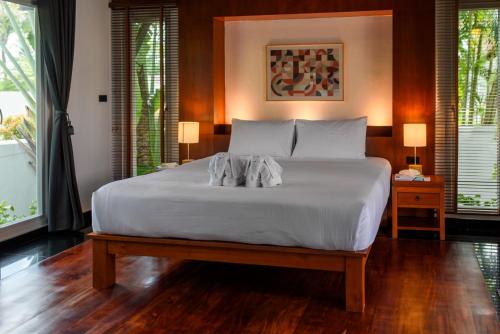 - une chambre avec un grand lit blanc et 2 fenêtres dans l'établissement Luxurious Residence Rawai, à Phuket