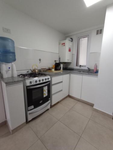 uma cozinha com um fogão e armários brancos em Departamento del centro em Neuquén