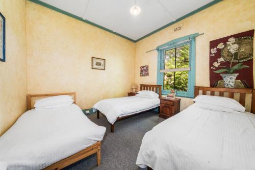 two twin beds in a room with a window at Brigalow Cottage in Leura