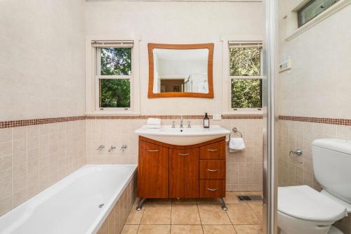 a bathroom with a tub and a sink and a toilet at Brigalow Cottage in Leura