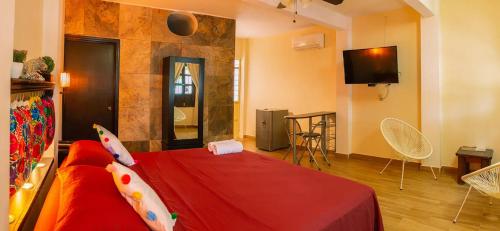 a bedroom with a red bed and a flat screen tv at Oasis Maya in Tuxtla Gutiérrez