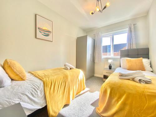 a bedroom with two beds and a window at Oakley House - Spacious 3 Bedroom, Garden and Parking in Corby