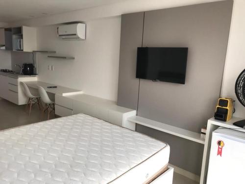 Habitación blanca con cama y TV de pantalla plana. en MANAÍRA APART HOTEL en João Pessoa